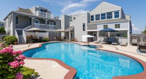 Exterior view of the property with light gray shake siding, patio with patio furniture, and pool