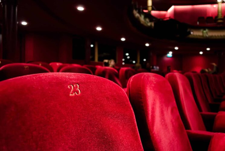 Rows of red velvet seats in a dark theatre